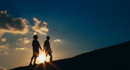 pareja-al-atardecer-sobre-un-fondo-de-cielo-azul-y-nubes-se-eleva-sobre-una-colina
